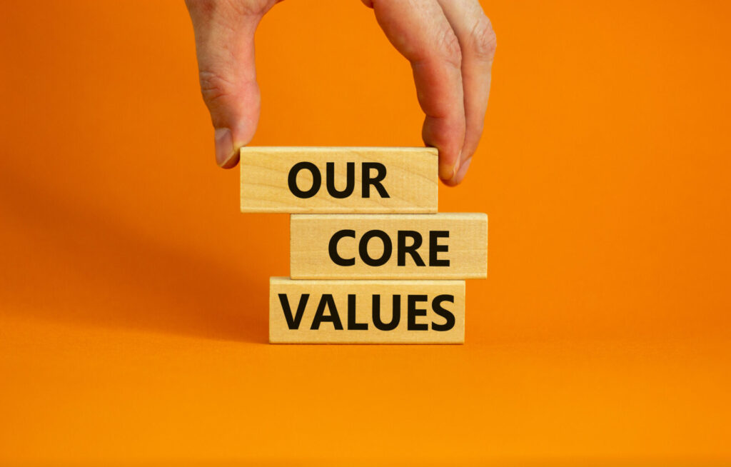 our core values symbol. concept words 'our core values' on wooden blocks on a beautiful orange background, businessman hand. business and our core values concept. copy space.