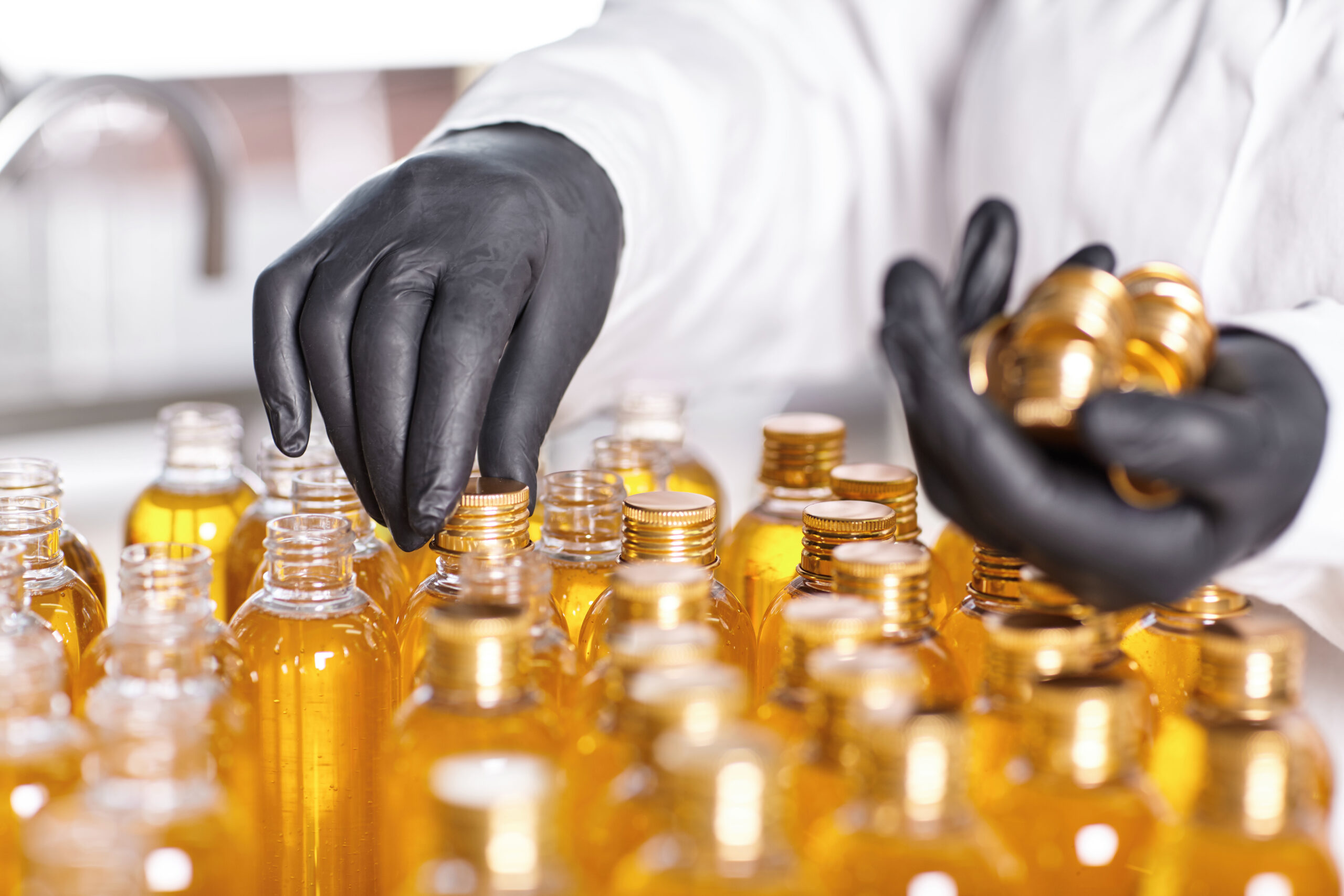 Factory worker filling and capping bottles at Glamcos Lifestyle facility